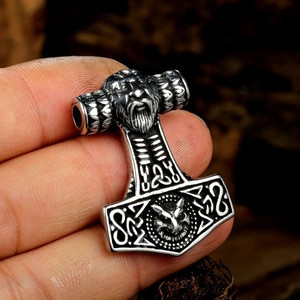 Macro shot of Viking Mjölnir pendant with Thor's face and wolf head totem carvings