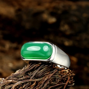 Macro shot of oval green gemstone ring on rustic wood base with a vintage aesthetic