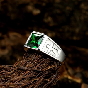 Macro shot of silver titanium ring featuring a square green gemstone and cross relief