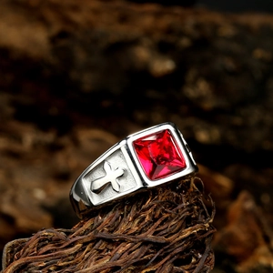 Close-up of gothic men's stainless steel ring featuring square red gemstone and cross relief
