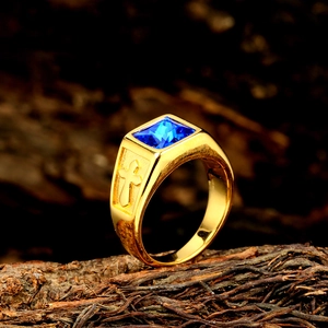 Macro shot of gold-plated stainless steel ring with blue gemstone and cross carving