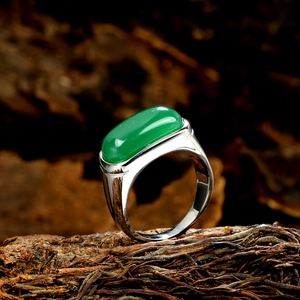Macro detail of retro stainless steel ring with rectangular green gemstone on wood
