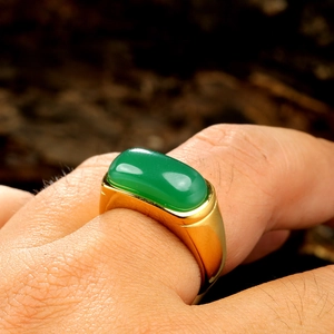 Detailed close-up of a vintage gold steel ring featuring a large rectangular green gemstone