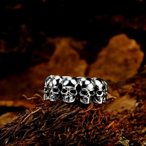 Gothic style multi-skull mens ring in vintage silver finish on rustic wood background