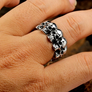 Close-up of gothic men's skull ring featuring five detailed skulls on a metal band