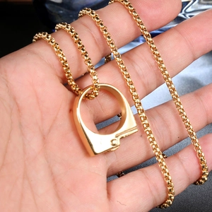 Detailed close-up of golden handcuffs pendant on round box chain held in hand