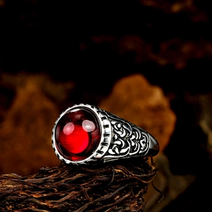 Détail d'une bague punk vintage argentée avec grosse pierre rouge et gravures en relief