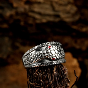 Vintage stainless steel wide snake ring with red crystal eyes on natural wood background
