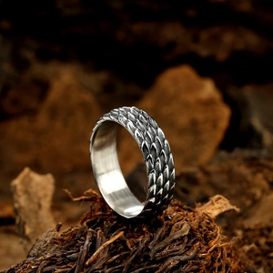 Retro stainless steel ring with dragon scale texture on rustic wood background