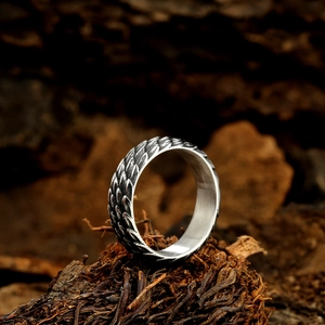 Retro stainless steel dragon scale ring with polished inner band on natural wood