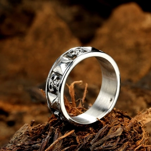 Gothic skull and anchor embossed silver metal ring for men displayed on natural wood bark