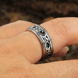 Macro detail of retro silver ring featuring intricate vine patterns and rope edges