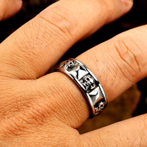 Macro view of vintage silver ring featuring embossed skull and hourglass gothic patterns