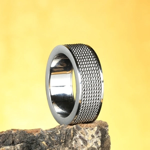 Fashionable rotatable woven mesh ring in silver stainless steel on rock background