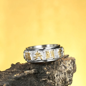 Detail of silver spinner ring with golden nine-word mantra characters on a wood stand