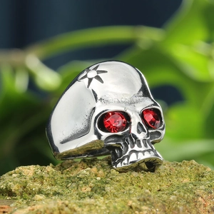 Macro view of a skull ring with red rhinestone eyes on a mossy rock outdoor