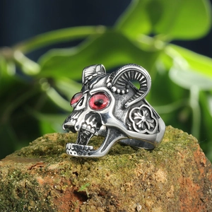 Macro detail of gothic goat head ring with red eyes on mossy vintage brick stone