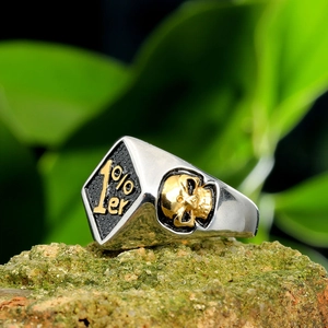 Detailed macro shot of vintage 1%er motor biker ring with gold skull on a rock