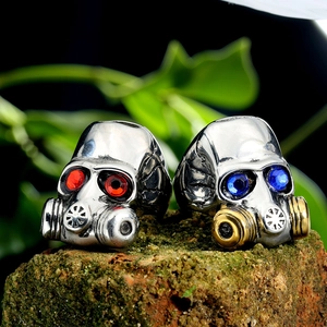 Gothic punk skull gas mask rings with red and blue gem eyes on a rustic brick