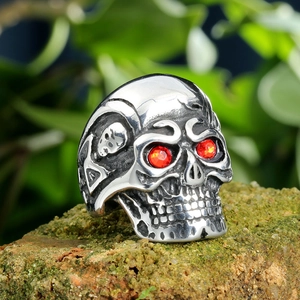 Macro shot of punk skull ring with red eye stones on natural mossy rock background