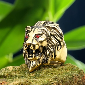 Macro shot of lion head ring with vintage gold finish and red rhinestone eyes on mossy stone