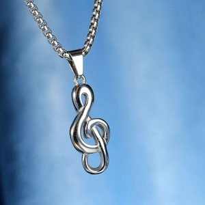 Macro d'un pendentif clé de sol en argent avec chaîne sur fond bleu texturé