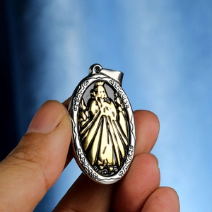 Religious oval copper pendant with goddess relief shown being held for size scale