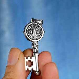 Macro view of St. Benedict silver steel key pendant with cross cutout and religious coin