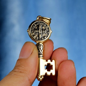 Detailed close-up of golden Saint Benedict key pendant with engraved religious symbols