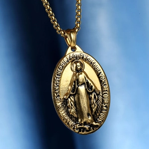 Detailaufnahme des goldenen Jungfrau Maria Anhängers mit Box-Kette auf blauem Samt