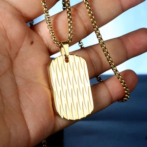 Detail of a gold-plated stainless steel rectangular pendant with a textured ripple finish