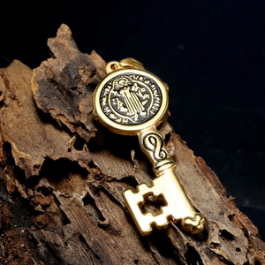 Vintage gold stainless steel key pendant with Saint Benedict medal on dark wood