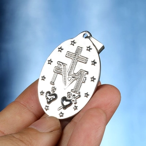 Makro-Detail von ovalem Edelstahl-Anhänger mit religiösem Kreuz M und Herz-Symbolen
