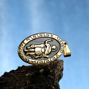 Détail du pendentif ovale doré avec relief de guerrier noir et bordure grecque