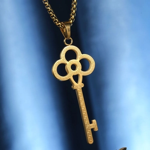 Elegant gold clover key necklace with Greek key patterns on textured blue background