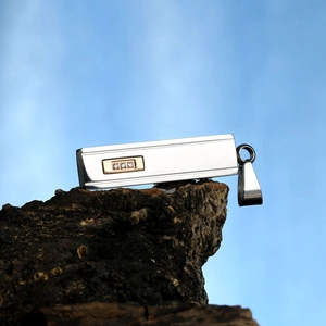 Macro shot of silver titanium steel pillar pendant with gold inlay and three clear zircons