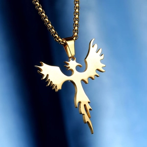 Macro shot of golden phoenix pendant with box chain on dark blue silk background