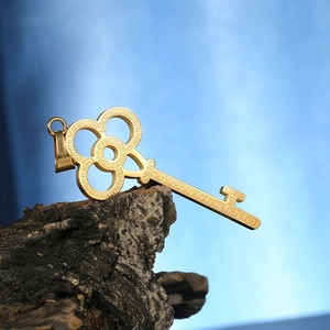 Macro shot of gold-plated key pendant with Greek fret pattern and clover cutout detail