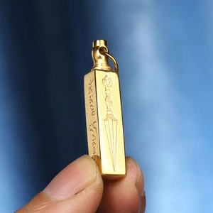 Détail d'un pendentif religieux rectangulaire doré avec des écritures tibétaines gravées