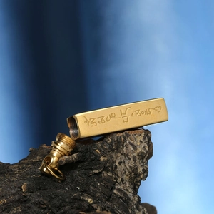 Vue macro du pendentif flacon de parfum en acier inoxydable doré avec gravures sacrées