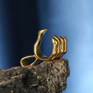 Bague main de squelette dorée style hip-hop avec design punk sur support bois