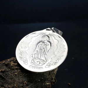 Vue macro du pendentif ovale Vierge Marie en acier inoxydable sur bois sombre