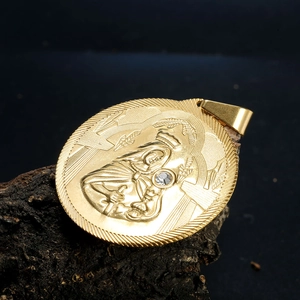Détail macro du relief de la Vierge Marie sur pendentif ovale doré avec zircon brillant