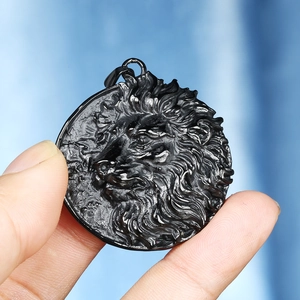 Detailed macro view of a black lion head relief pendant with matte volcanic rock texture