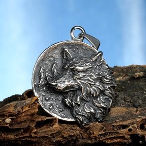 Macro detail of antique silver wolf head pendant with textured fur and rocky background