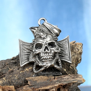 Close-up of gothic punk skull pendant with iron cross on rustic bark background