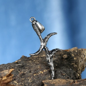 Detailed macro view of vintage silver dagger pendant on rustic tree bark texture