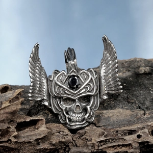Gothic winged skull pendant in stainless steel with black gemstone on wood bark