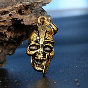 Macro shot of gold and black punk skull pendant on rustic wood with vintage finish