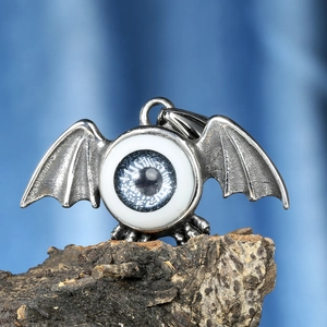 Gothic bat wing pendant with blue eye stone on dark wood background, vintage style necklace